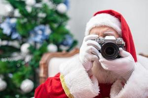 Babbo Natale che tiene una macchina fotografica d'epoca. ritratto isolato su sfondo giallo. foto
