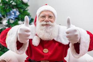 Babbo Natale che mostra il pollice in su. babbo natale con barba vera e grande sorriso che dà pollice in su. foto