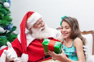 Babbo Natale consegna una confezione regalo a una bambina. vigilia di natale, consegna di regali. foto