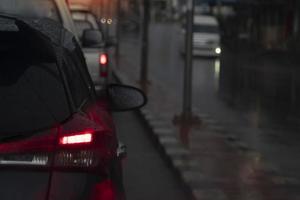 astratto e sfocato delle auto posteriori sulla strada durante la stagione delle piogge. accendere la luce del freno su strada asfaltata con blocco stradale al centro della strada. foto