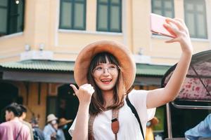 giovane ragazza asiatica di influenza che viaggia a Bangkok con lo smartphone per il caricamento sul social network. foto