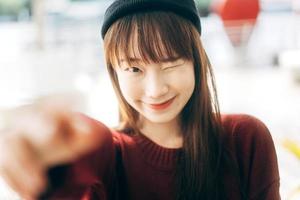 il ritratto di giovane donna asiatica sveglia dell'allievo dell'adolescente indossa un maglione rosso foto