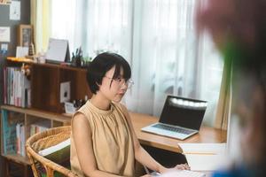 la giovane donna asiatica adulta rimane e lavora dall'ufficio a casa tramite internet online. foto