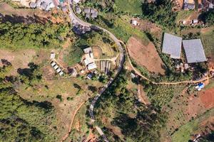 veduta aerea del villaggio rurale locale con strada sterrata attraverso nella valle in lontananza in campagna tra la foresta pluviale tropicale foto