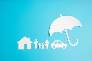 copertura dell'ombrello carta a forma di famiglia, casa e auto su sfondo blu. giornata internazionale delle famiglie, assistenza sanitaria, benessere e concetto assicurativo foto