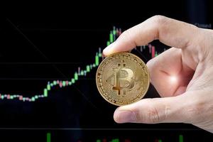 moneta di criptovaluta bitcoin dorato con sfondo grafico a candela, la cripto è denaro digitale all'interno della rete blockchain, viene scambiata utilizzando la tecnologia e lo scambio Internet online. concetto finanziario foto