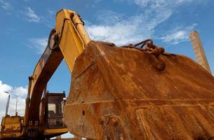 primo piano secchio di metallo arrugginito del vecchio retroescavatore parcheggiato in cantiere contro il cielo blu. macchina da scavo. macchina movimento terra. veicolo di scavo. secchio di sporcizia del vecchio escavatore. industria di costruzioni. foto