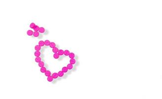 le compresse rosa sono disposte a forma di cuore isolate su sfondo bianco. piccole compresse rosa pillole di warfarin. farmaci anticoagulanti. concetto di cuore e amore. medicina per il trattamento delle malattie cardiache. foto
