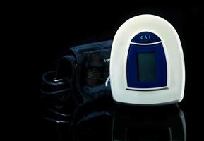 sfigmomanometro digitale blu-bianco con bracciale ad ampia gamma isolato su sfondo scuro. concetto di controllo sanitario foto