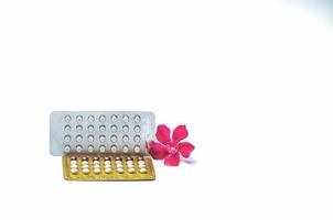 pillole contraccettive o pillole anticoncezionali con fiore rosa isolato su sfondo bianco. ormone per la contraccezione. concetto di pianificazione familiare. compresse ormonali in blister. sfondo della farmacia. foto