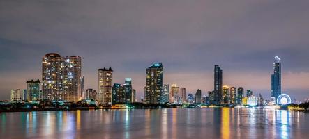 paesaggio urbano di un edificio moderno vicino al fiume nella notte. edificio per uffici di architettura moderna. grattacielo con cielo serale. immagine in tono bianco e nero. fotografia notturna dell'edificio sul lungofiume. foto