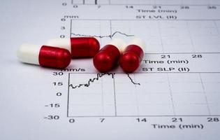 carta per referto grafico elettrocardiogramma ekg o ecg. risultato del test da sforzo est e capsule rosso-bianche. promozione del pacchetto per il controllo del cuore nel concetto di persone anziane o anziane. foto