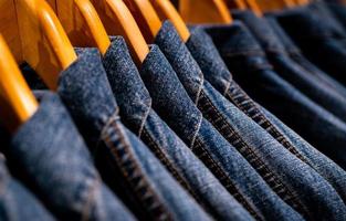 messa a fuoco selettiva sui jeans della giacca appesi sul rack nel negozio di abbigliamento. jeans denim con motivo jeans. industria tessile. jeans moda e concetto di shopping. concetto di abbigliamento. giacca di jeans su rack in vendita. foto