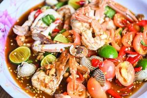 insalata piccante frutti di mare su vassoio, insalata cucina tailandese piccante delizioso frutti di mare con granchio gamberetti vongole calamari e spezie ingrediente limone lime pomodoro peperoncino fresco cibo piccante foto