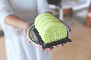 la donna ha servito il pandan verde del rotolo di torta con crema - rotolo di torta sul piatto foto