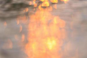 luce solare astratta riflettente sullo sfondo dell'acqua, luci bokeh sulla superficie dell'acqua al tramonto natura estate o primavera oceano mare foto