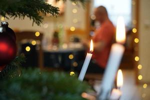 lume di candela di cera sull'albero di Natale verde. e silhouette di persone foto