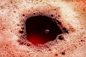 immagine rosso scuro di schiuma sulla superficie del liquido. sfondo astratto di schiuma rossa. foto