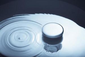 immagine minimalista di un bicchiere d'acqua con una gocciolina caduta sulla superficie dell'acqua. immagine astratta di acqua in bianco e nero blu. foto