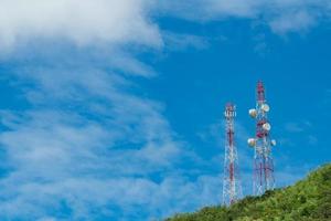 torre delle telecomunicazioni sulla montagna e albero verde con cielo blu. antenna sul cielo blu. polo radio e satellitare. Tecnologia della comunicazione. settore delle telecomunicazioni. rete mobile o di telecomunicazione 4g. foto