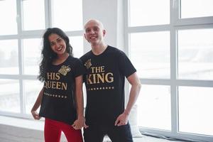 iscrizioni color oro. il re e la sua regina. uomo e donna in camicia nera in piedi nella stanza vicino alle finestre foto