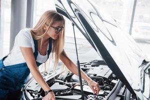 necessita di un piccolo ritocco. sul bel lavoro. la donna dipendente dall'auto ripara l'automobile nera all'interno foto