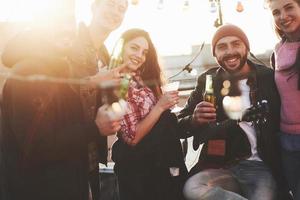 tutti guardano in una telecamera. è una festa sul tetto. un gruppo di amici ha vacanze in una soleggiata giornata autunnale foto