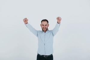 successo atteso. uomo in abiti ufficiali si trova su sfondo bianco in studio foto