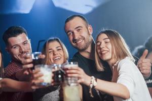 tempo libero. persone felici che ballano nel night club di lusso insieme a diversi drink nelle loro mani foto