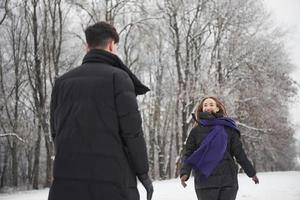 finalmente incontrato. la splendida giovane coppia si diverte insieme nella foresta innevata foto