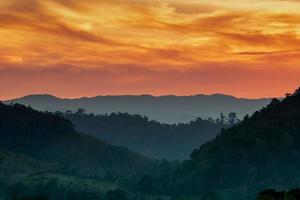 bellissimo paesaggio naturale della catena montuosa con cielo al tramonto e nuvole. valle di montagna in tailandia. scenario di strato montuoso al tramonto. foresta tropicale. sfondo naturale. cielo arancione e dorato. foto