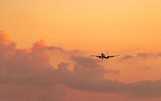 compagnia aerea commerciale. aereo passeggeri che atterra in aeroporto con un bellissimo cielo al tramonto e nuvole. voli in arrivo. aereo che vola in linea per l'atterraggio. l'aeromobile apre la luce nel volo serale. foto