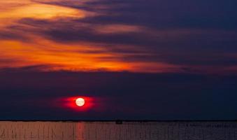 bellissimo tramonto sul mare. cielo e nuvole al tramonto rosso scuro e arancione. sfondo della natura per un concetto tranquillo e pacifico. tramonto a chonburi, in tailandia. grande sole emotivo al tramonto. cielo crepuscolare. foto