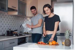 fare insalata e dessert. giovane coppia nella cucina moderna a casa durante il fine settimana al mattino foto