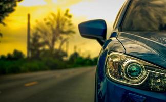 vista frontale di un'auto suv compatta blu di lusso con design sportivo e moderno parcheggiata su strada asfaltata al tramonto. auto ibrida e concetto automobilistico. viaggio su strada e guida in auto per il viaggio. foto