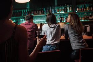 la ragazza con il vetro sta andando dagli amici. la bella giovinezza fa festa insieme all'alcol in discoteca foto