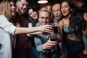 immagina se ogni giorno sarà un fine settimana. gruppo di giovani amici che sorridono e fanno un brindisi in discoteca foto