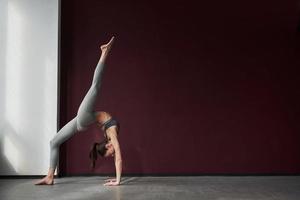 guida per lo yoga. la ragazza con una buona forma fisica fa esercizi nella stanza spaziosa foto