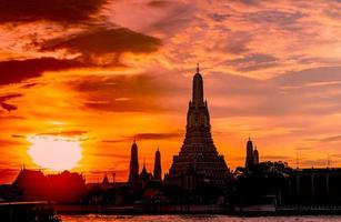 wat arun ratchawararam al tramonto con un bel cielo arancione e nuvole. il tempio buddista di wat arun è il punto di riferimento a bangkok, in tailandia. arte di attrazione e architettura antica a bangkok, in tailandia. foto