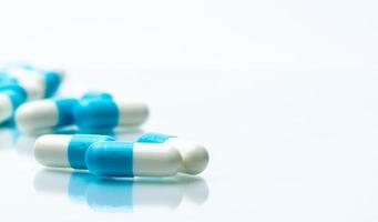mucchio di capsule blu e bianche pillole isolate su sfondo bianco con ombre e copia spazio per il testo. concetto di assistenza sanitaria globale. foto