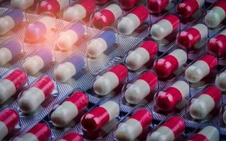 Pillole di capsule di antibiotici rosa-bianco e blu-bianco in confezione blister. resistenza ai farmaci antimicrobici. industria farmaceutica. assistenza sanitaria globale. sfondo della farmacia. capsule di amoxicillina. foto