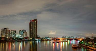 paesaggio urbano di un edificio moderno vicino al fiume nella notte. edificio per uffici di architettura moderna. grattacielo con cielo serale. immagine in tono bianco e nero. fotografia notturna dell'edificio sul lungofiume. foto