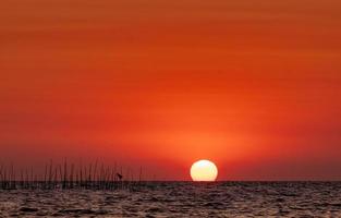 grande sole sul mare al tramonto. bellissimo cielo e skyline al tramonto. cielo rosso romantico per uno sfondo pacifico e tranquillo. sfondo di ispirazione e citazione. bellezza nella natura. scena della spiaggia estiva. oceano. foto