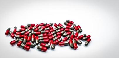 mucchio di pillole capsule rosso-grigie su sfondo bianco. industria farmaceutica. prodotto della farmacia della farmacia. produzione farmaceutica. farmaceutici. concetto di assistenza sanitaria globale. molte delle pillole della capsula. foto