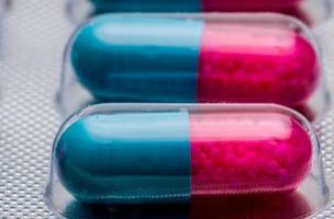 ripresa macro dettaglio della capsula blu, rosa con granulo in pillole laterali. pillole in blister. forma farmaceutica e confezionamento. itraconazolo 100 mg medicinale antimicotico. foto
