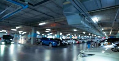 sfoca il parcheggio sotterraneo del centro commerciale con la luce aperta. sfocare la guida dell'auto e le persone che camminano all'interno del garage sotterraneo. macchina affollata parcheggiata in un moderno parcheggio sotterraneo. foto