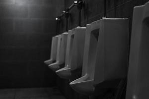 orinatoi bianchi nel bagno pubblico degli uomini. orinatoi in ceramica in fila nel bagno degli uomini. salute della vescica dell'uomo con il concetto di problema di incontinenza urinaria. infezioni urinarie. latrina maschile wc. toilette maschile comfort. foto