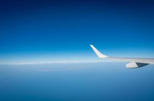 ala dell'aereo su nuvole bianche. aereo che vola sul cielo blu. vista panoramica dalla finestra dell'aeroplano. volo di una compagnia aerea commerciale. ala dell'aereo sopra le nuvole. concetto di meccanica di volo. volo internazionale. foto