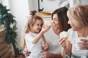 guarda questo delizioso pezzo di torta. madre, nonna e figlia che si divertono in cucina foto