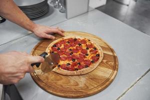 immagine di una deliziosa pizza preparata con anelli di salsiccia e olive foto
